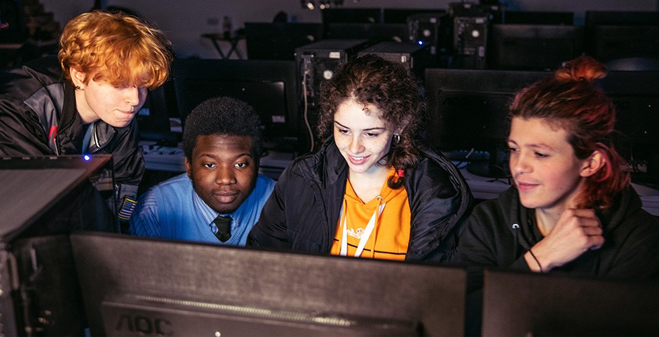 a group of students smiling at a computer