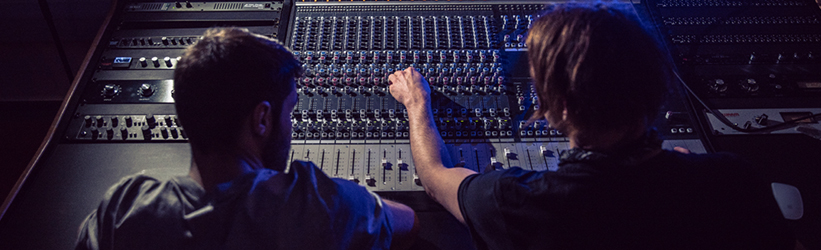 Two people using a mixing desk