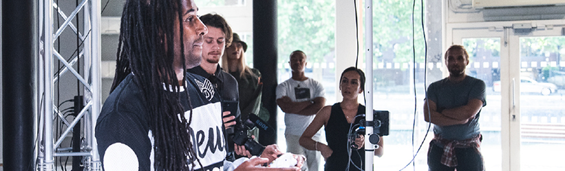 A group of people watching a male use a games controller