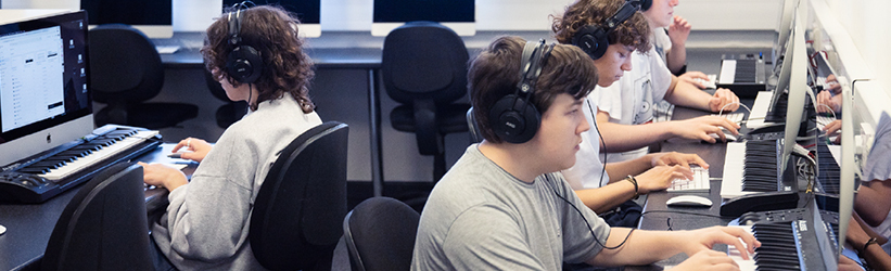 A group of people working at computers with MIDI keyboards
