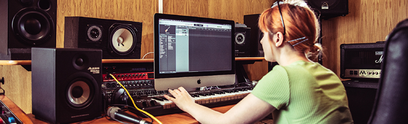 A female working at a computer with a MIDI keyboard