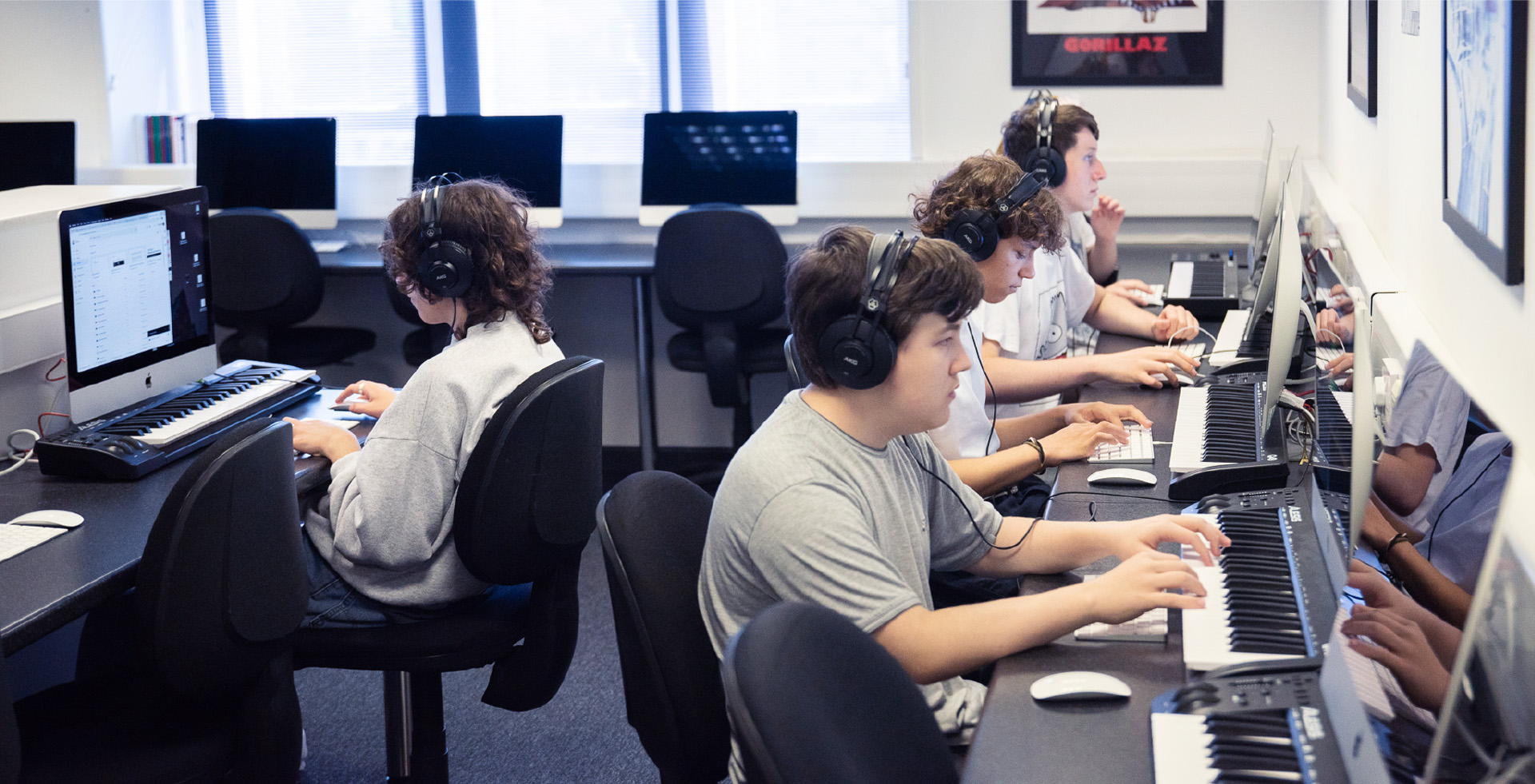 Group of males working at computers with MIDI keyboards