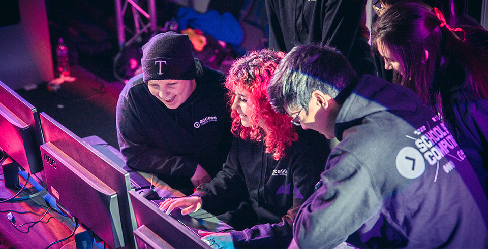 A group of students smiling surrounding a computer