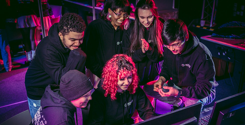 A group of college students smiling around a computer
