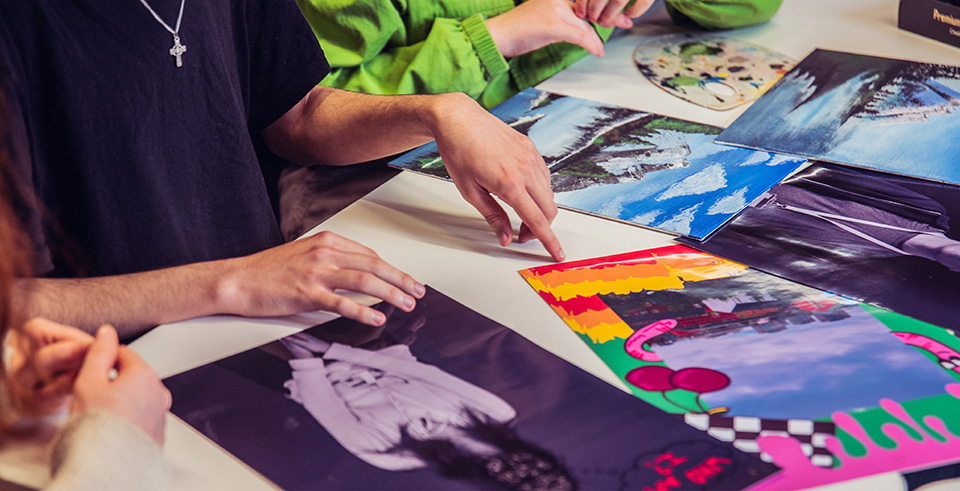 A group of people pointing at printed images on a desk