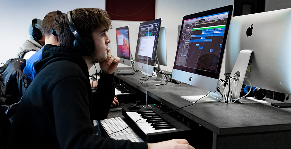 A group of males working at computers with MIDI keyboards