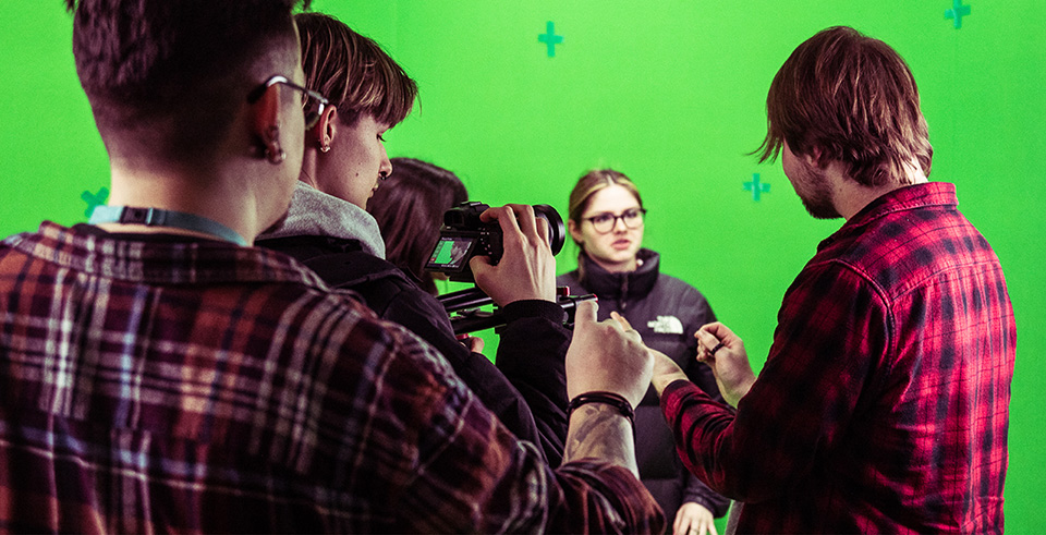 a group of young people filming in front of a green screen