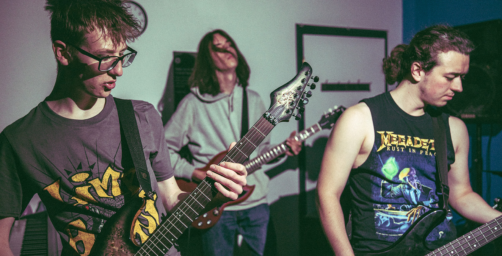 three students playing guitar