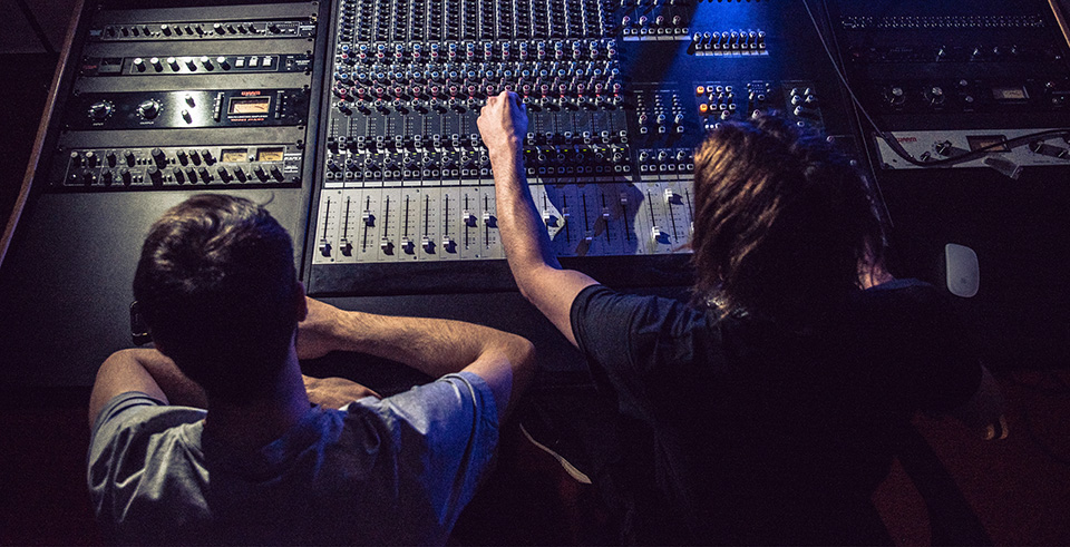 two students sat behind a sound desk