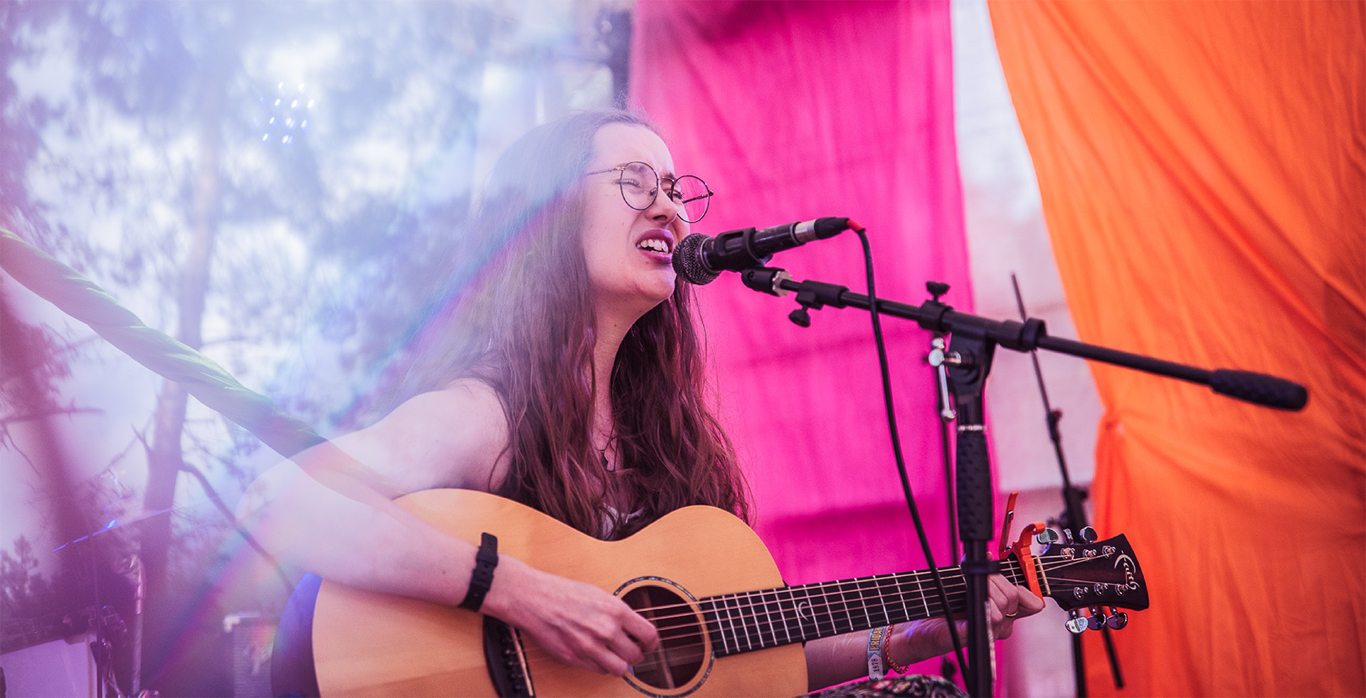 A person performing on stage with an acoustic guitar