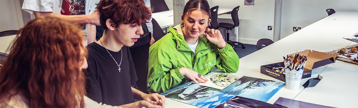 A group of people pointing at printed images on a desk