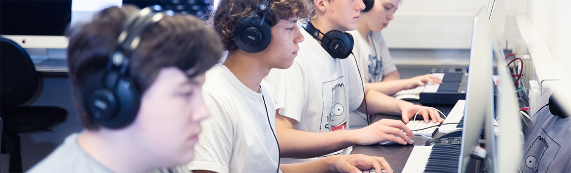 A group of people working at computers with MIDI keyboards