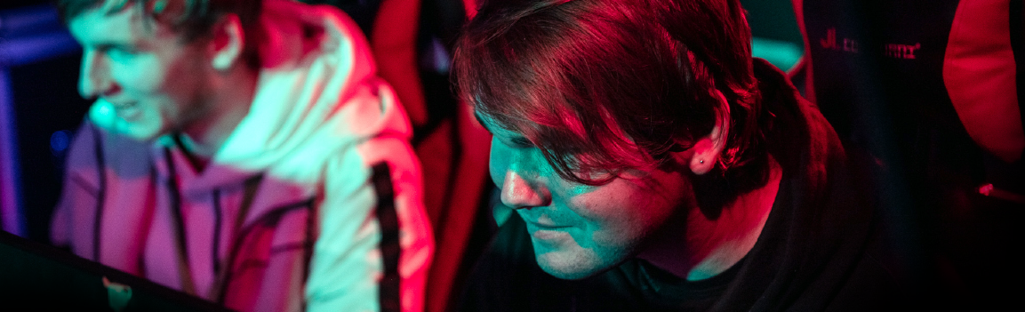 Two smiling males sat in gaming chairs