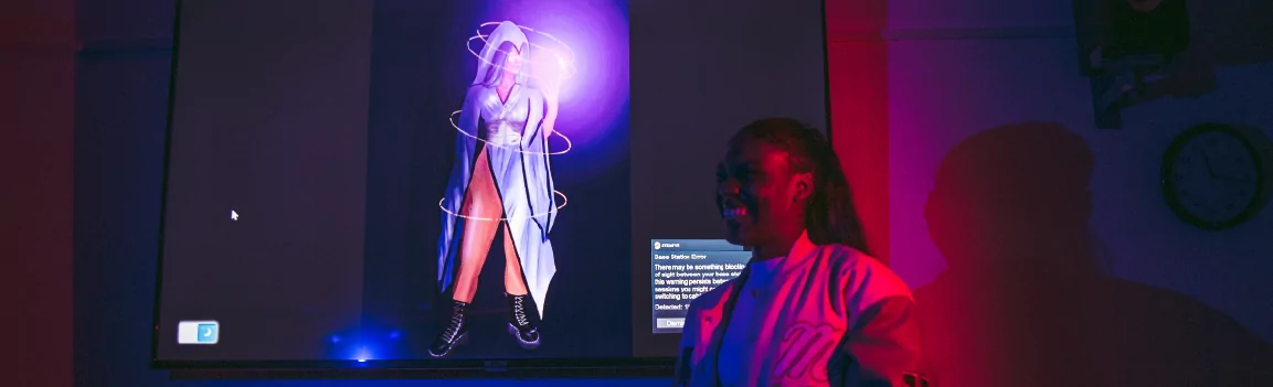 Smiling female stood next to projected image of game character artwork