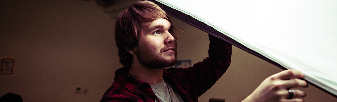 A male adjusting studio lighting
