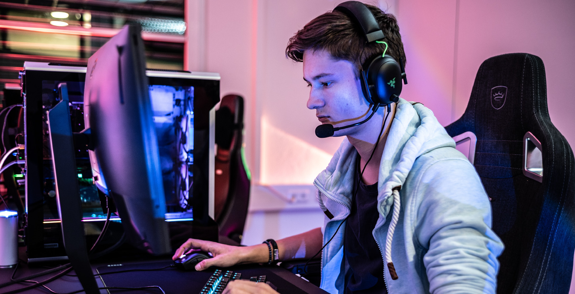 A person working at a computer, sitting in a gaming chair with gaming headphones