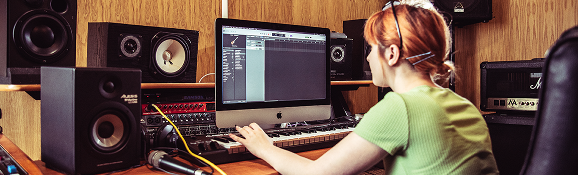 A female working at a computer with a MIDI keyboard