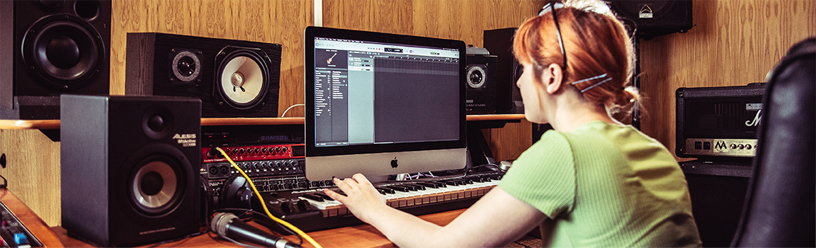 A female working at a computer with a MIDI keyboard