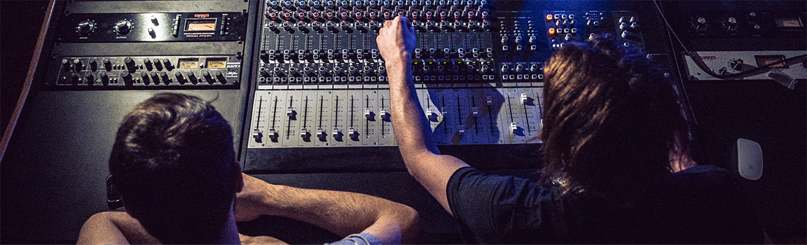 Two people working at a music mixing desk