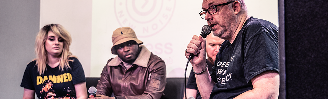 A group of people watching a male speak into a microphone