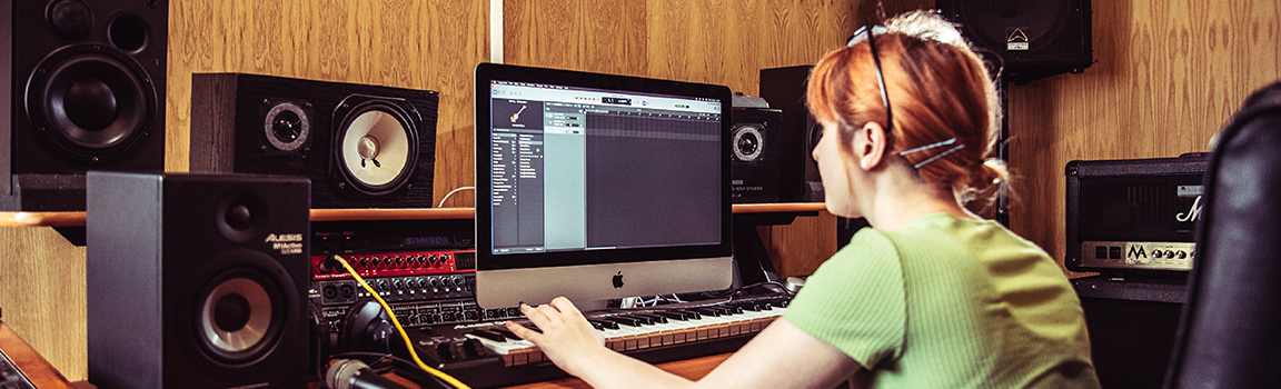 A female working at a computer with a MIDI keyboard