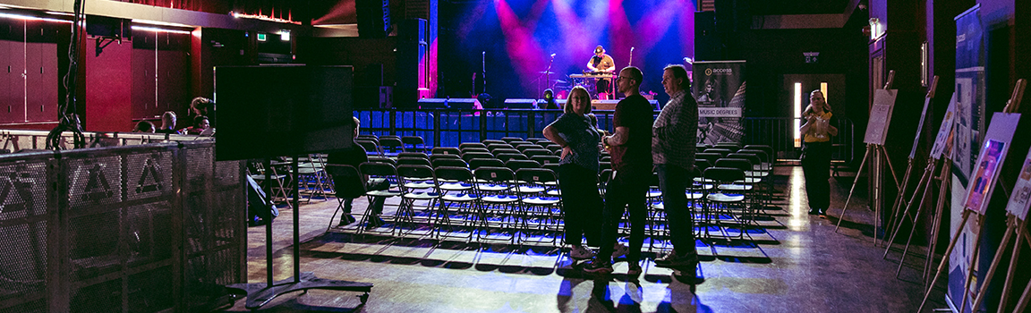 An empty venue with rows of chairs and a group of people talking in the foreground