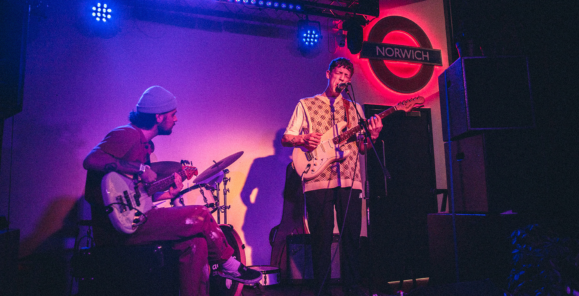 two students on stage singing and playing guitar