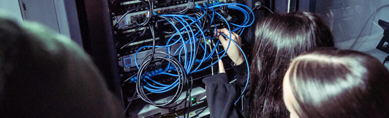 Two females working on a server filled with wires