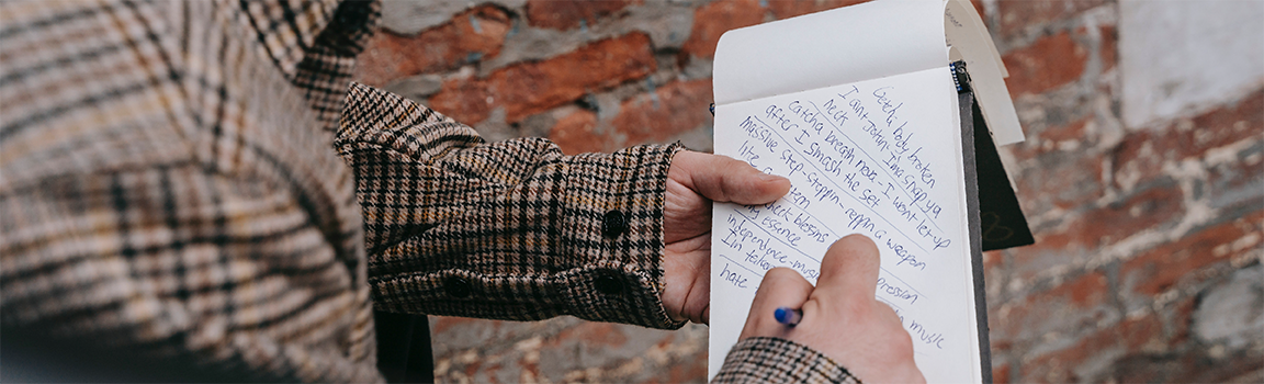 A person writing lyrics on a notepad
