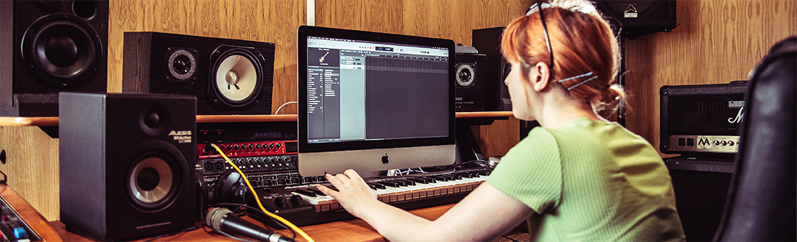 A female working at a computer with a MIDI keyboard