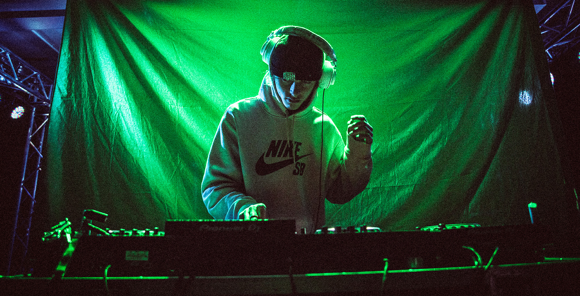 A male with over-ear headphones working at DJ decks