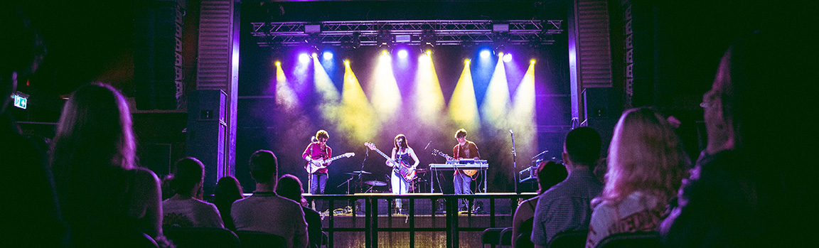 A crowd of people watch a band perform on stage
