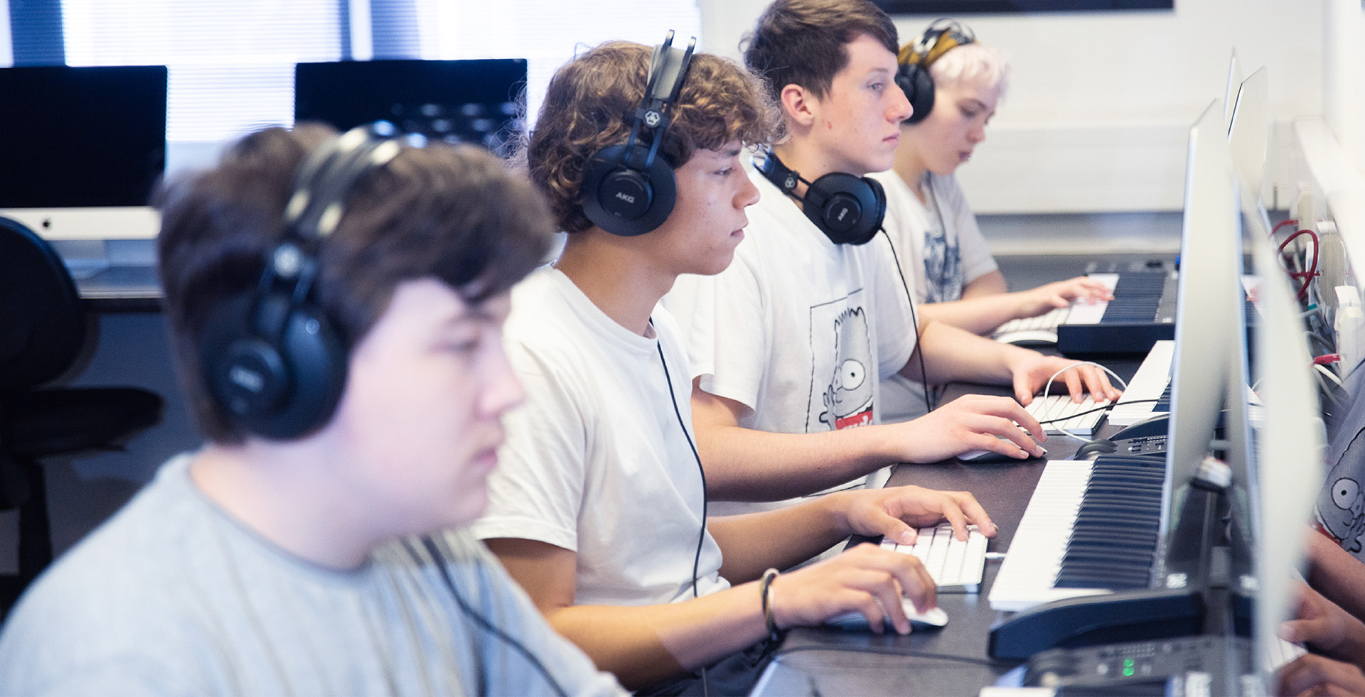 A group of people working at computers with MIDI keyboards