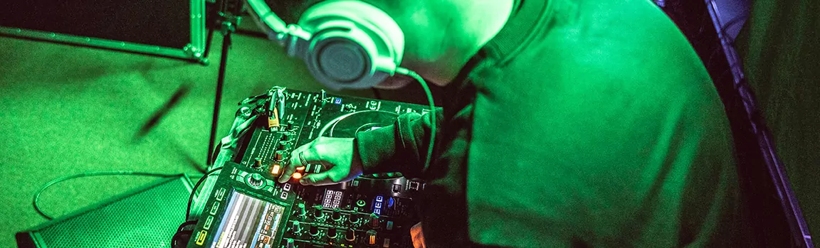 A man wearing over-ear headphones, working at DJ decks