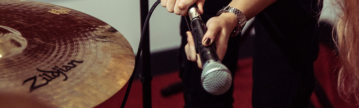 A person adjusting a microphone next to a drum cymbal