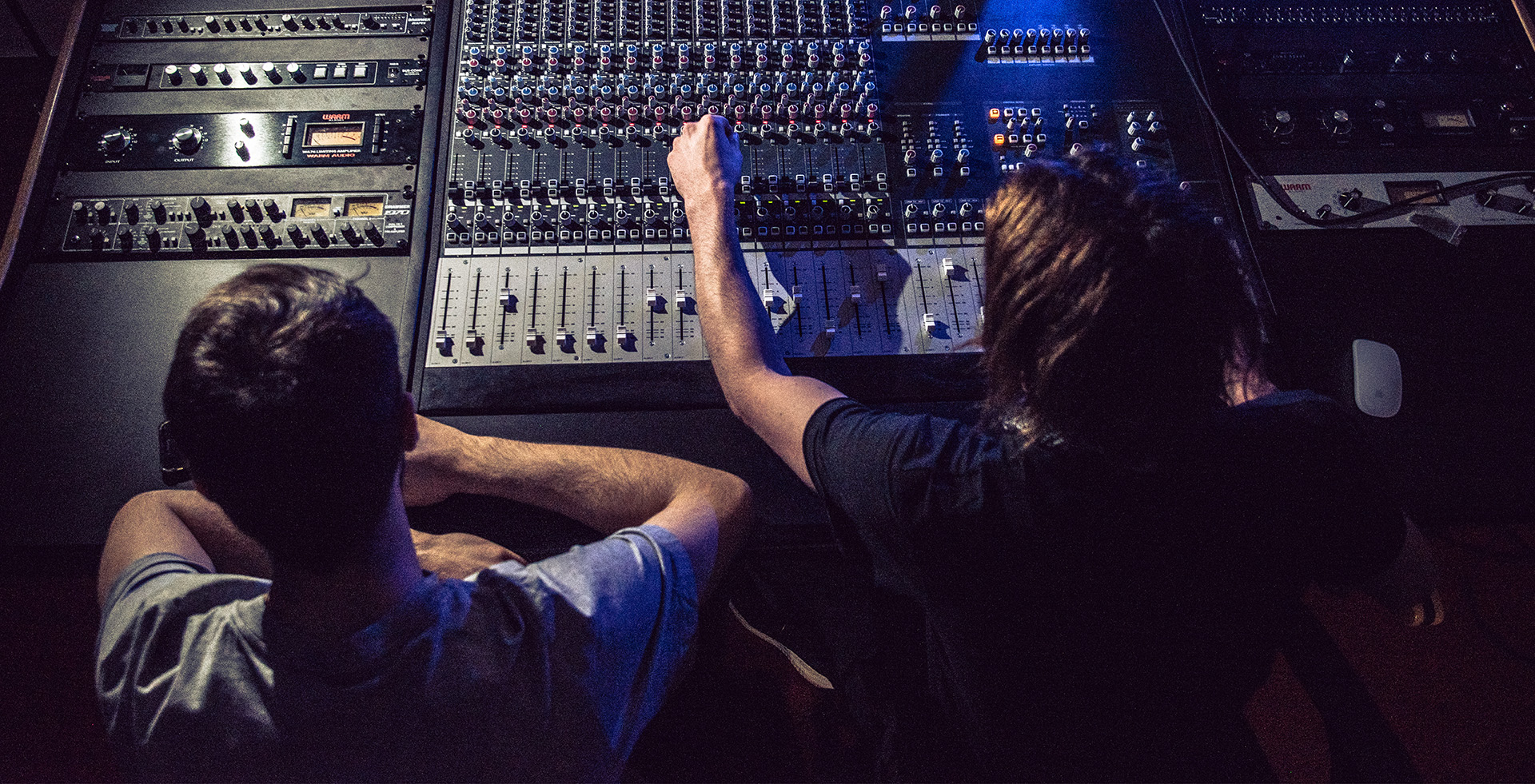 Two people working at a music mixing desk