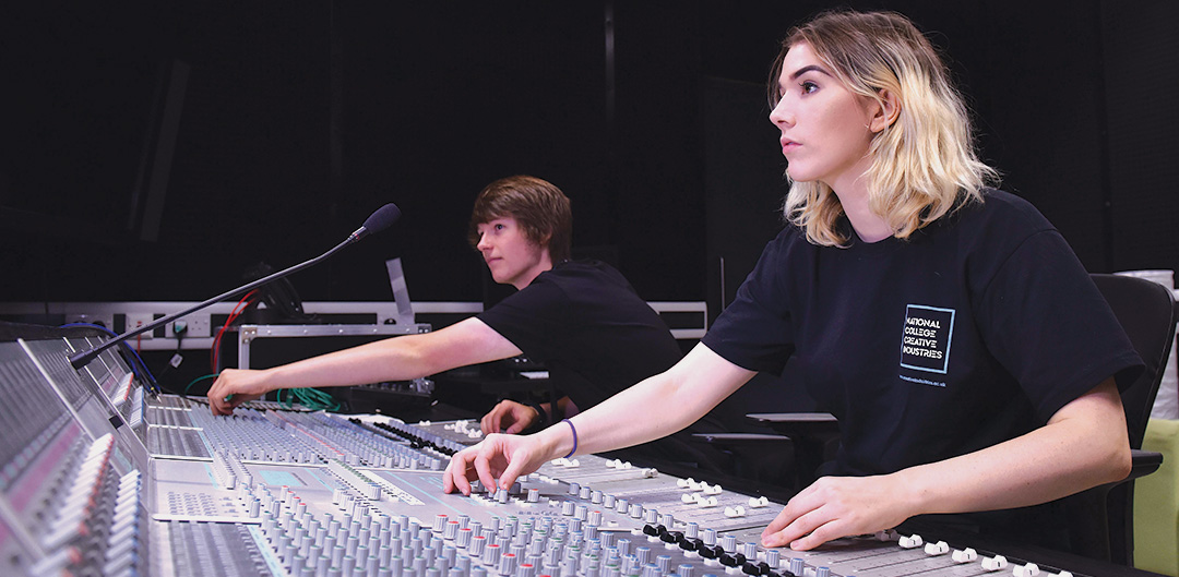 Two people working at a music mixing desk