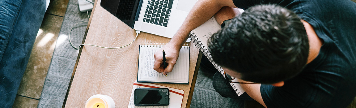 A person working at a desk, writing on a notepad