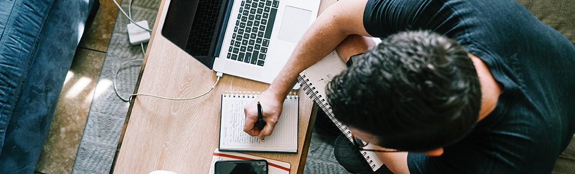 A person writing in a notepad at a desk