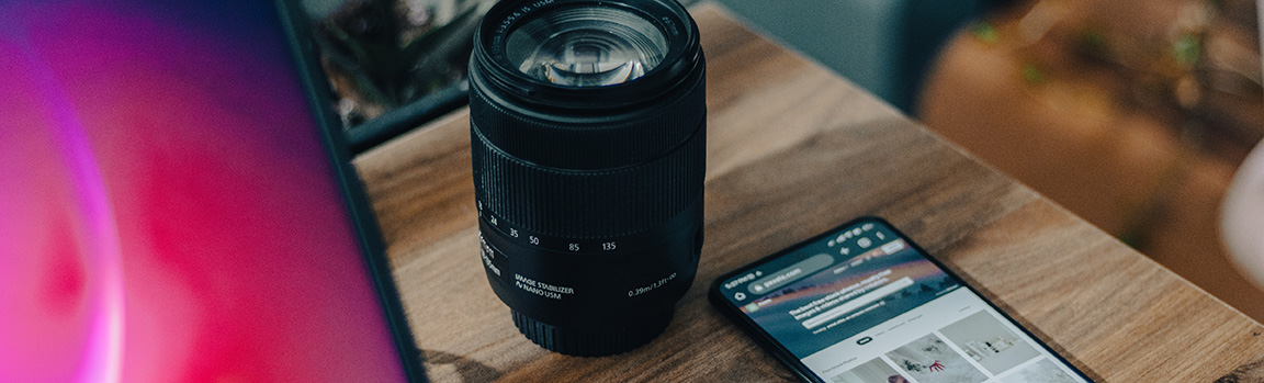 A camera lens and phone on a desk