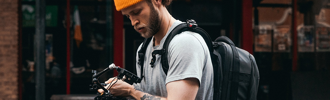 A person filming outdoors, wearing a backpack