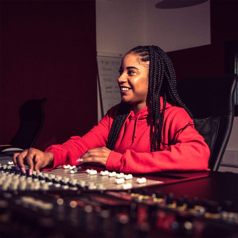 A person sat at a music studio mixing desk