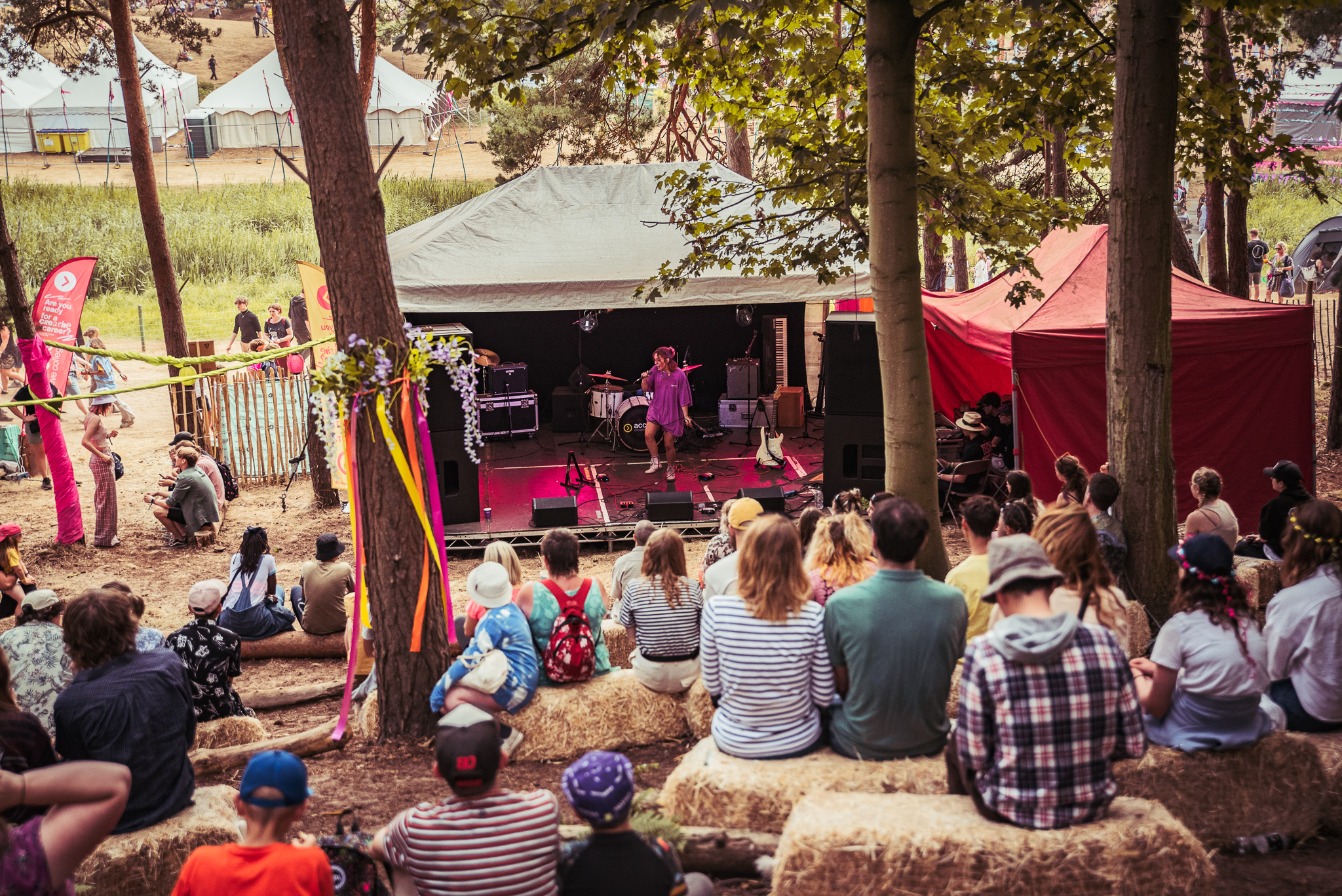 A woman performing with an audience watching while sat on hay bales