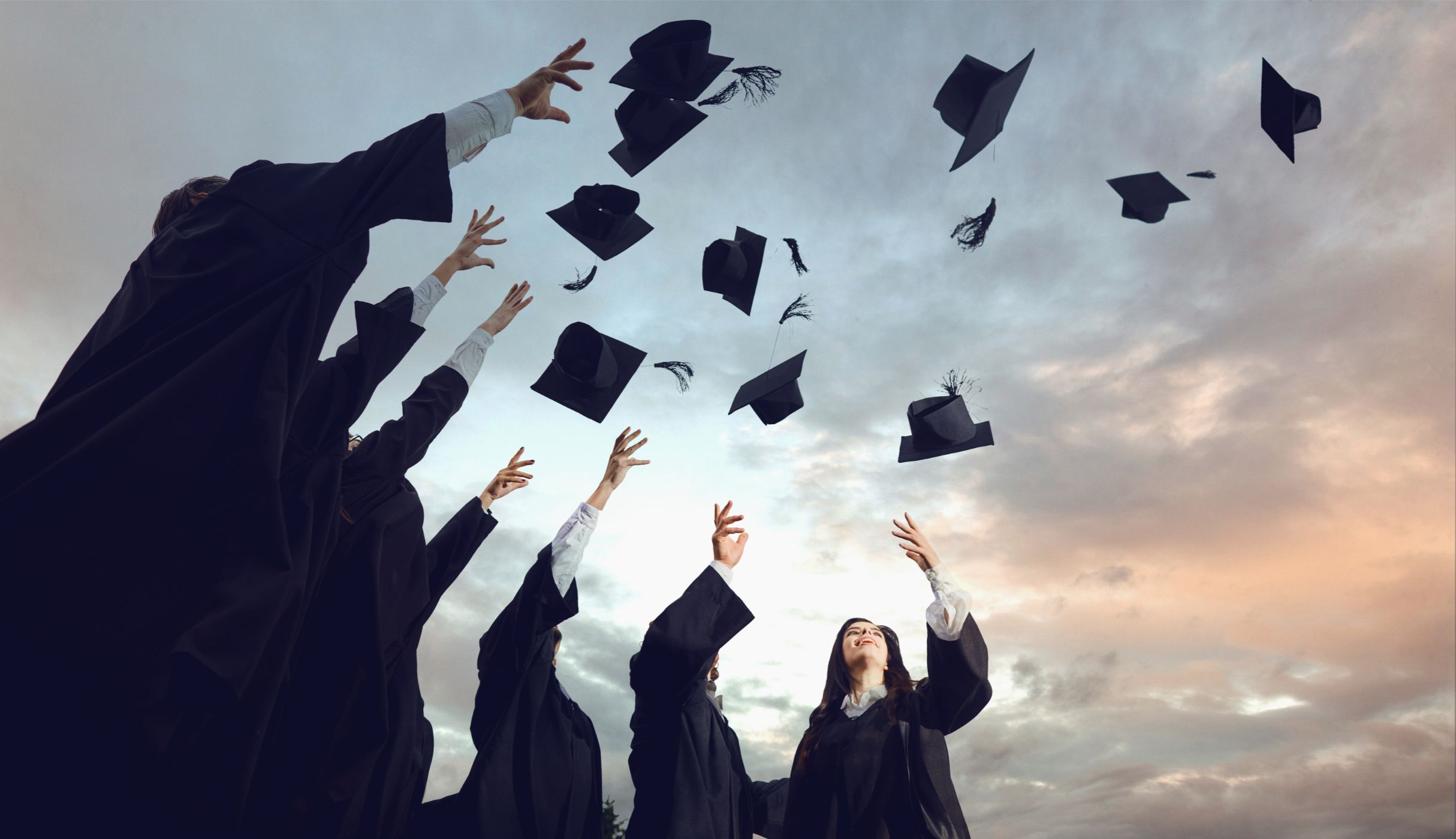 Students graduating together, throwing hats in the air