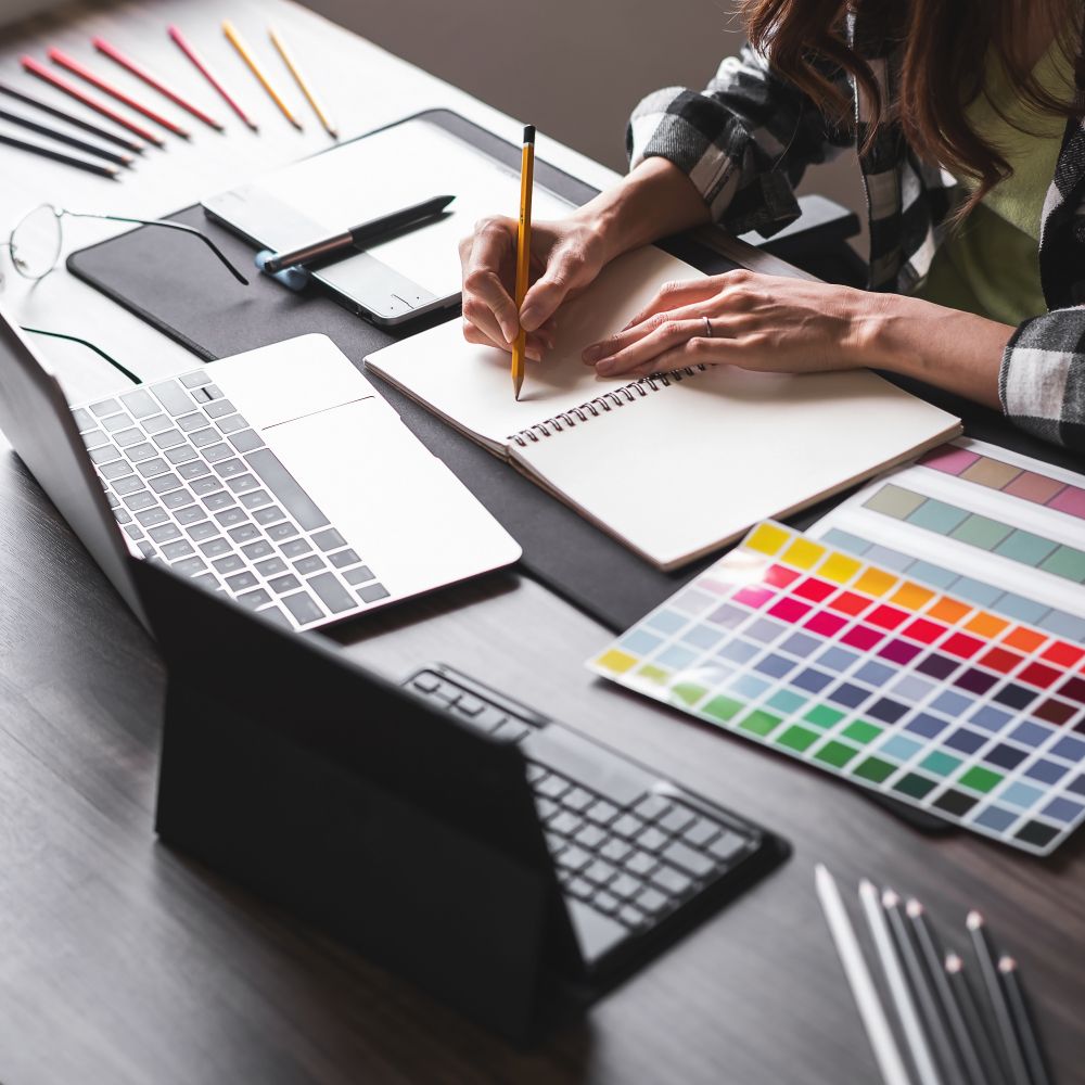 Graphic Design and Game Design: What's the difference? 4 Graphic designer working on social media graphics, using notepad, colour schemes and laptop