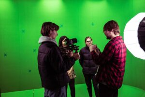 Student holding camera in green screen room